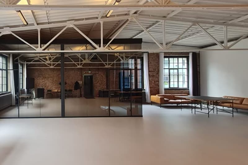 Ein verglaster Nebenraum in Werkraum.01, rechts die Lounge und ein Tisch